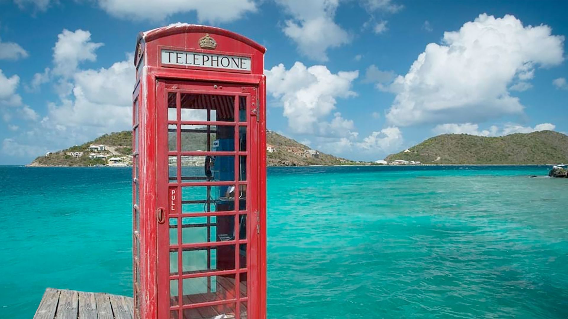 A Red Telephone Booth On A Dock Over Water